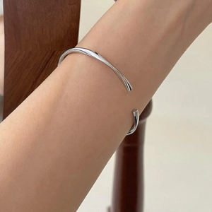 Minimalist silver geometric mobius cuff bracelet shown on wrist with polished finish