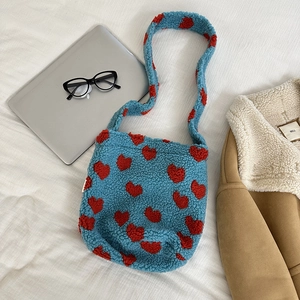 Detail of blue faux shearling tote bag with red heart pattern in a cozy winter setting