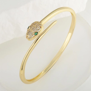 Exquisite gold snake bangle with sparkling white zircons and green emerald eyes