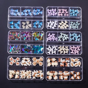 Detailed view of six organized boxes with colorful resin nail art charms and butterflies