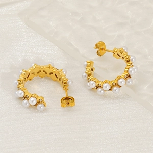 Créoles en C dorées avec perles et zircons sur fond texturé blanc de luxe élégant