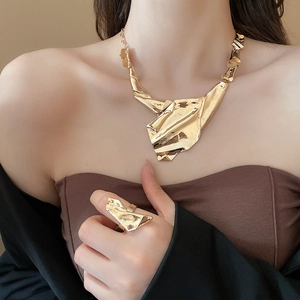 Detail of model wearing a gold irregular geometric necklace with wrinkled metal texture