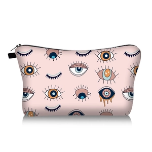 Close-up of pink cosmetic bag with cartoon evil eye patterns and black zipper detail
