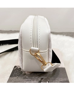 Detail of the white quilted crossbody bag showing gold zipper and stitching quality