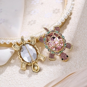 Detailed view of turtle brooches with pink crystals and rhinestones in golden setting