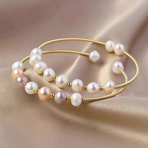 Detailed macro of gold spiral metal wire bracelet with multicolored pearls on silk