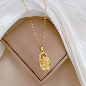 Close-up of gold Virgin Mary pendant necklace with zircon halo on beige jewelry box