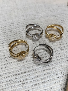 Detailed view of intertwined knot earrings with pavé crystals in gold and silver finish