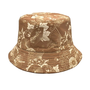 Close-up of brown bucket hat with traditional beige fan and floral patterns on canvas