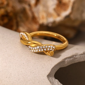 Detailed close-up of a twisted gold ring with sparkling white zircon stones on stone