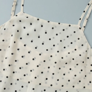 Detail of white polka dot camisole with thin straps and lightweight chiffon texture