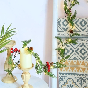 Christmas pine needle garland with red berries, pine cones and warm LED lights