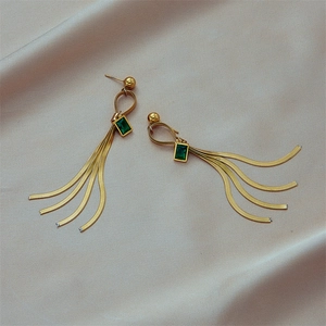 Golden titanium steel tassel earrings with green rectangular stones on silk background