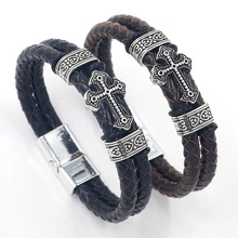 Close-up of woven leather bracelets with silver cross charms in black and brown