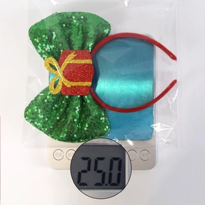 Detailed view of 25g Christmas headband with a large green sequined bow and red gift box