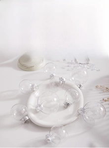 Close-up of clear Christmas ball ornaments with silver caps on a festive white table