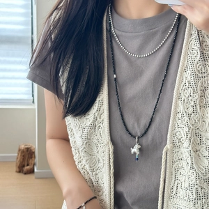 Bohemian black beaded layered necklace with a silver poodle pendant on a grey T-shirt