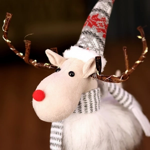 Close-up of plush Christmas reindeer with knitted hat, scarf, and glowing LED antlers