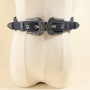 Detailed close-up of dark blue elastic belt featuring dual embossed metal buckles on a mannequin