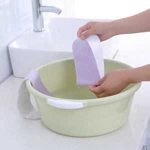 Copriwater adesivo viola lavabile mentre viene pulito in una bacinella d'acqua