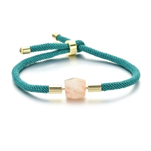 Detail of teal braided Milan rope bracelet with gold clasp and faceted peach gemstone