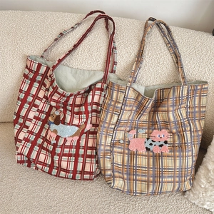 Detail of canvas tote bags with plaid patterns and animal embroidery on a white sofa