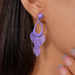 Detail view of purple matte drop earrings with hollow leaf tassels on a model