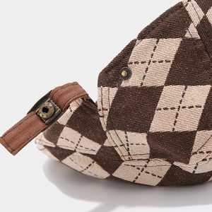 Detailed macro view of the brown argyle fabric and metal buckle on the vintage flat cap