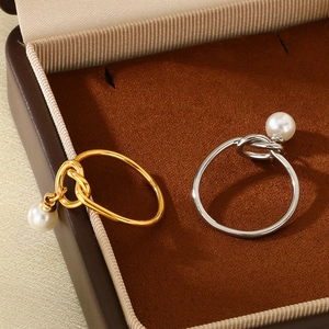 Elegant gold and silver knot rings with white pearls displayed in a premium velvet box