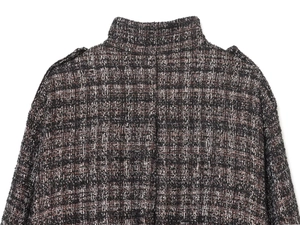 Macro detail of neutral tweed bomber jacket showing shoulder straps and woven texture