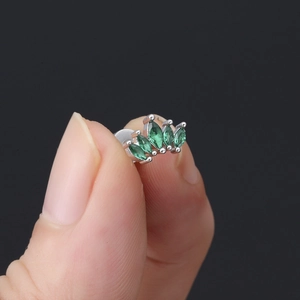 Gros plan d'une boucle d'oreille couronne sertie de cinq zircons verts de taille marquise