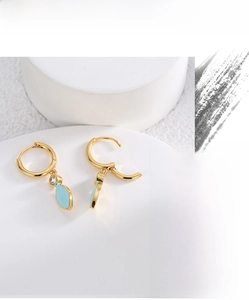 Detailed shot of golden hoop earrings with sky blue leaf pendants and sparkling zircon stones