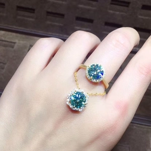 Macro shot of 3ct blue-green moissanite pendant and ring in gold-plated settings