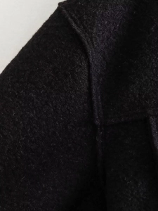 Close-up of black woolen fabric showing soft texture and premium collar stitching detail