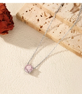 Detail of pink rose-cut gemstone pendant on silver chain against stone background