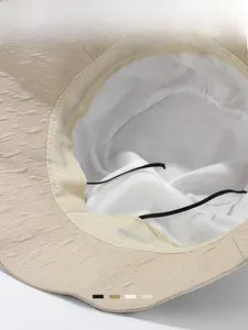 Detail shot of beige sun bucket hat with white cotton lining and adjustable chin strap