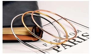 Close-up of three 2mm minimalist bangles in gold, silver, and rose gold polished finish