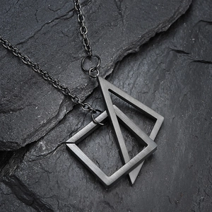 Close-up of interlocking triangle and square titanium steel pendants on a slate background
