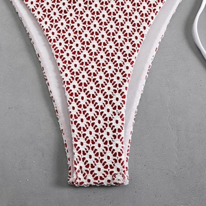 Detailed view of white crochet lace bikini bottom with red lining and floral cutouts