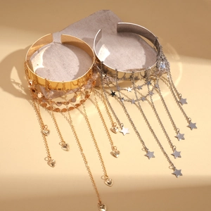 Detailed view of gold heart and silver star tassel bangles on stone textured display