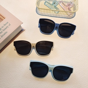 Overhead view of three cat-eye kids sunglasses in blue and beige on a textured background