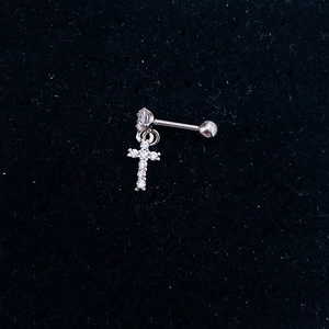 Macro view of silver cross ear cuff with sparkling zircons on a dark velvet background