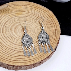 Detail of vintage silver bohemian drop earrings with ethnic metal tassels on wood