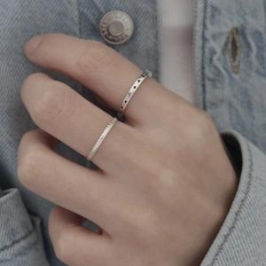 Close-up of 925 sterling silver star ring and woven band on model against denim