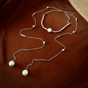 Macro shot of silver pearl tassel necklace on silk fabric showing detailed craftsmanship