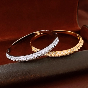 Detail of 18K gold and silver plated bangles with rivet studs and pave-set zircons