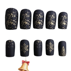 Christmas press-on nails with matte black base, gold snowflakes, and tree patterns