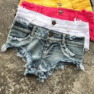 Dettaglio di pantaloncini in denim a vita bassa con orli sfrangiati e strappi