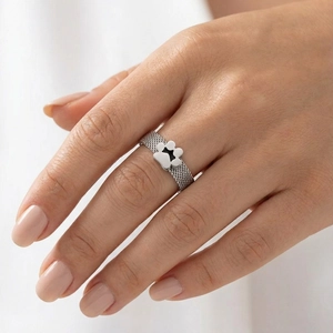 Close-up of silver mesh ring with a black paw print charm on a model's hand