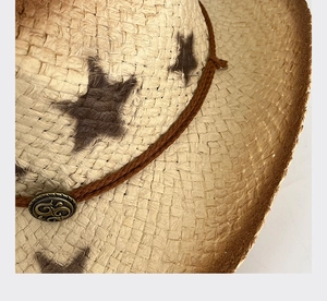 Close-up of natural straw cowboy hat with star pattern and vintage metal buckle detail